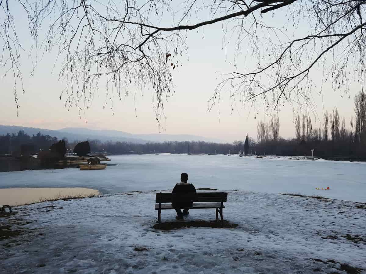 冬の中暖かい服で湖を見つめる人